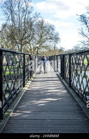 personnes traversant la rivière cam à un vieux pont piétonnier en fer Banque D'Images