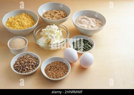 Ingrédients dans des bols pour un pain bas carb sain avec des protéines, de la farine de grain entier et des graines, recette maison de cuisson pour l'obésité et le diabète, t bois Banque D'Images