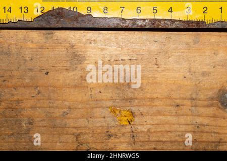 Ancienne règle jaune rouillée avec numéros noirs sur une table en bois en état de marche. Arrière-plan industriel. Atelier de menuiserie avec espace de copie Banque D'Images