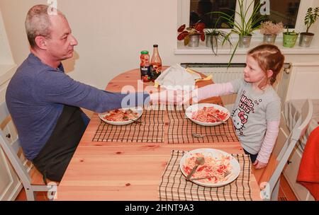 Fille et père dans la cuisine manger des spaghetti pour le dîner Banque D'Images