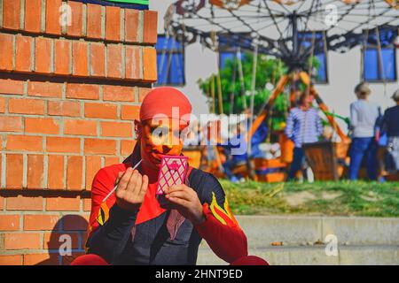 Un artiste de rue qui se fait le maquillage du visage. Les artistes de rue peuvent tromper les passants et divertir les touristes. Banque D'Images