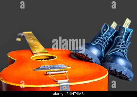 Rock and Roll concept. Bottes noires et guitare acoustique. Rock and Roll bottes sur fond rose Banque D'Images