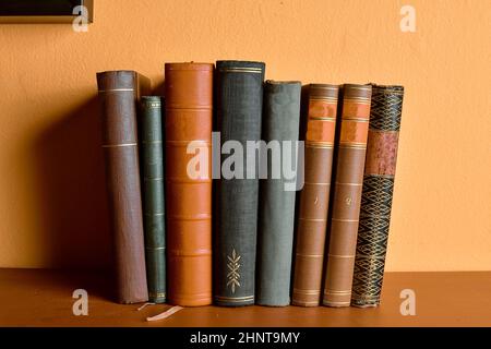 Rangée d'anciens livres reliés. Livres anciens sur fond jaune et bordeaux Banque D'Images