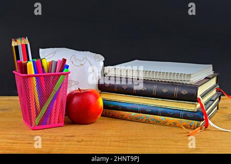 Concept de l'école déjeuner pause avec pomme et fournitures scolaires sur bureau en bois, foyer sélectif. Livres, marqueurs et crayons de couleur mettant l'accent sur le concept. Il est temps d'étudier et de se détendre. Banque D'Images