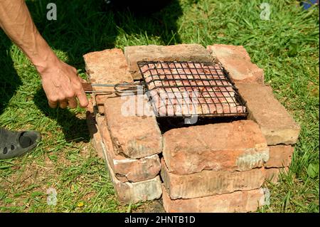 Le kebab de shish est frit sur un gril sur des charbons et des briques Banque D'Images