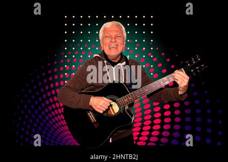 Homme senior assis avec une guitare enregistrant une piste dans une maison Banque D'Images