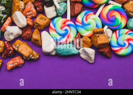 Sucettes et bonbons. Bonbons sous forme de pierres colorées. Fond coloré avec bonbons colorés. Décoration festive Banque D'Images