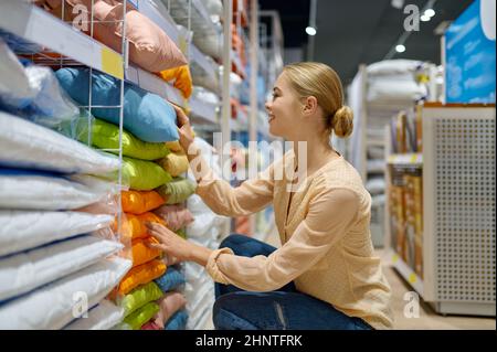 Souriante positive femme choisissant l'oreiller dans la boutique Banque D'Images