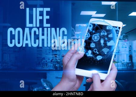 Affiche montrant le coaching de vie, mot écrit sur la personne employée pour aider à montrer leurs objectifs dans la carrière main touchant l'écran de téléphone mobile Showi Banque D'Images
