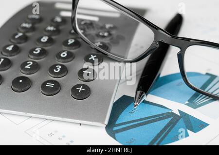Stylo, calculatrice et verres sur un arrière-plan de diagrammes.concept d'entreprise Banque D'Images