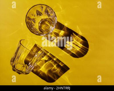 Deux verres en verre avec visages sur fond jaune dans une lumière dure avec ombres Banque D'Images