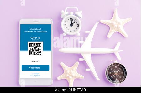 Modèle d'avion, passeport et carte d'immunité sont arrangés application sur smartphone sur fond violet, concept de Voyage pendant la digita pandémique Covid-19 Banque D'Images