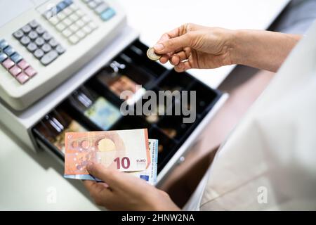 Main du caissier travailler avec la caisse enregistreuse changer la facture d'argent Banque D'Images