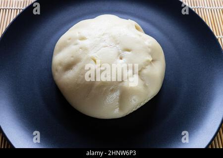 Bao de Banh cuit à la vapeur, petit pain rempli de sauce vietnamienne, sur une assiette noire Banque D'Images