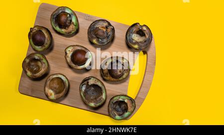Avocat surmûr sur un chipper en bois sur fond jaune. Pourriture des fruits Avocado dans la cuisine sur une table. Concept de nourriture inhelthy. Arrêtez de gaspiller de la nourriture. Copie s Banque D'Images