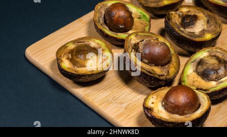 Rotten Avocados demi sur la table. Mauvais fruits sur le Chipper de bois. Gros plan sur l'avocat trop mûr. Banque D'Images