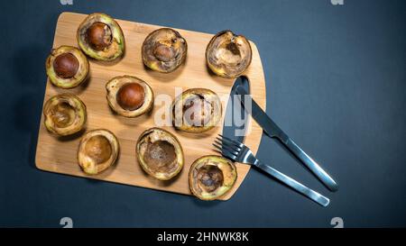 Avocat pourri sur le bois Chipper à côté fourchette et couteau. Unhelthy Food concept. Tout ce qu'il y a de mauvais repas. Mauvaise nourriture végétarienne. Petit déjeuner malsain. Copier l'espace. Banque D'Images