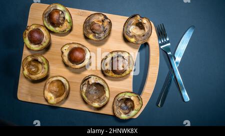 Avocat pourri sur le bois Chipper à côté fourchette et couteau. Unhelthy Food concept. Tout ce qu'il y a de mauvais repas. Mauvaise nourriture végétarienne. Petit déjeuner malsain. Copier l'espace. Banque D'Images