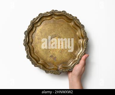 main femelle tenant une assiette vide en cuivre rond vintage sur fond blanc, plat de fruits.Vue de dessus Banque D'Images