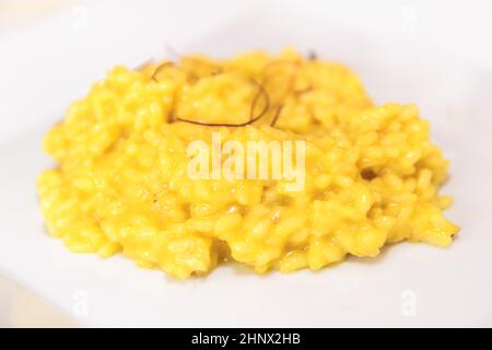 Assiette de riz au risotto jaune crémeux avec filets de safran de Milan, Italie.DOF peu profond. Banque D'Images