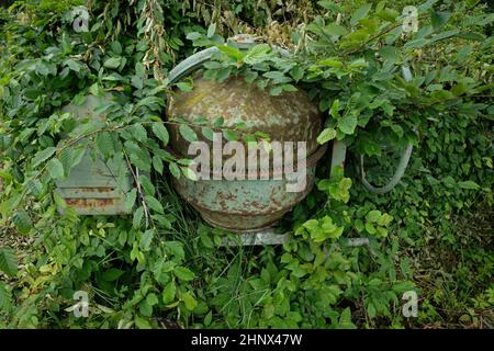 Vieux mélangeur de ciment avec de la rouille cultivée avec des plantes vertes gros plan Banque D'Images