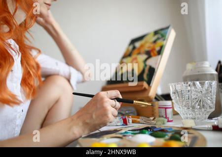 Femme artiste assis à la maison et peint une image Banque D'Images