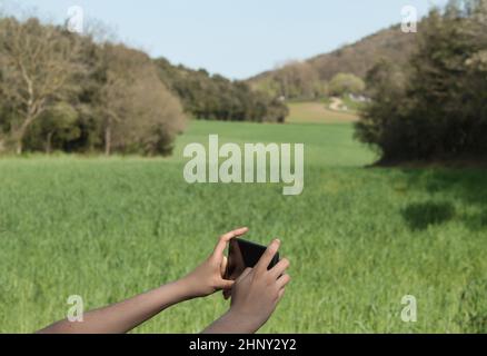 fille prenant une photo avec un mobile à un luxuriant pré Banque D'Images