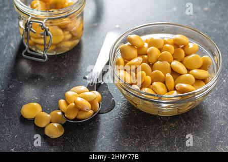 Haricots lupin jaunes marinés dans un bol sur une table de cuisine. Banque D'Images