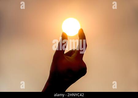 Une image conceptuelle de tenir le soleil à deux doigts. Banque D'Images