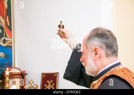 Un prêtre arménien tient une figurine d'oiseau dans sa main et exécute le rite du baptême sur la police. Russie, Rostov-sur-le-Don - 30 mai 2014 Banque D'Images