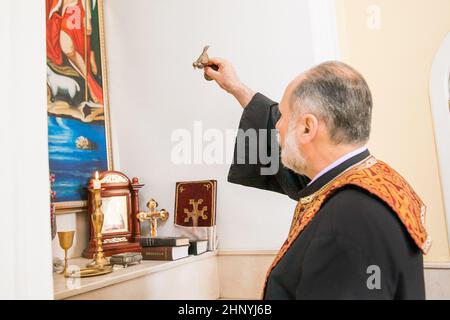 Un prêtre arménien tient une figurine d'oiseau dans sa main et exécute le rite du baptême sur la police. Russie, Rostov-sur-le-Don - 30 mai 2014 Banque D'Images