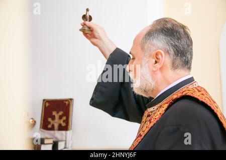 Un prêtre arménien tient une figurine d'oiseau dans sa main et exécute le rite du baptême sur la police. Russie, Rostov-sur-le-Don - 30 mai 2014 Banque D'Images