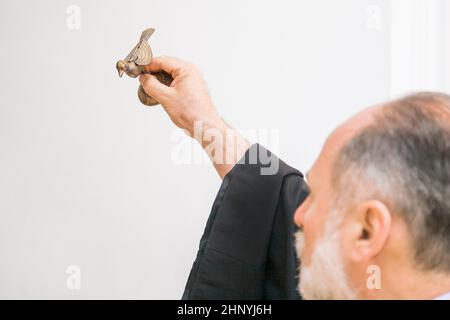 Un prêtre arménien tient une figurine d'oiseau dans sa main et exécute le rite du baptême sur la police. Russie, Rostov-sur-le-Don - 30 mai 2014 Banque D'Images