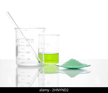 Sulfate ferreux dans le verre de surveillance chimique placer à côté du liquide sulfate de fer (II) dans le bécher.Gros plan sur l'ingrédient chimique sur la table de laboratoire blanche.Côté Banque D'Images