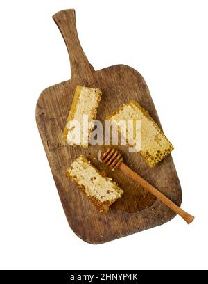 pile de cire nid d'abeille avec miel sur bois et cuillère en bois, fond blanc isolé, vue de dessus Banque D'Images