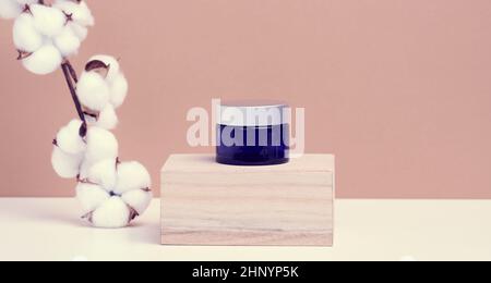 produits cosmétiques dans un pot en verre bleu avec un support de couvercle gris sur un podium en bois en cubes. Blanc pour les produits de marque, hydratant sur fond beige Banque D'Images