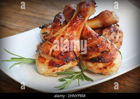 Cuisses de poulet grillées au romarin servi sur plaque blanche. Le dîner contexte . Banque D'Images