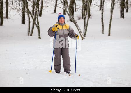 Une femme âgée en costume de ski skine un jour d'hiver. Banque D'Images