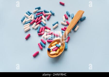 Diverses pilules sur fond bleu avec une cuillère en bois dans laquelle des vitamines Banque D'Images
