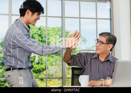 Les hommes d'affaires asiatiques âgés et jeunes se saluent au bureau. Joyeux vieux et junior deux hommes d'affaires saluent la main, l'accueil et le partenariat Banque D'Images