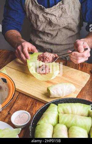 L'homme cuisine des rouleaux de chou farcis à la viande hachée dans la cuisine Banque D'Images