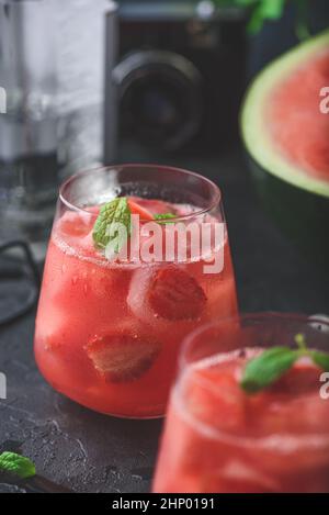 Cocktail frais avec garniture de pastèque, fraise et menthe sur fond de béton foncé Banque D'Images