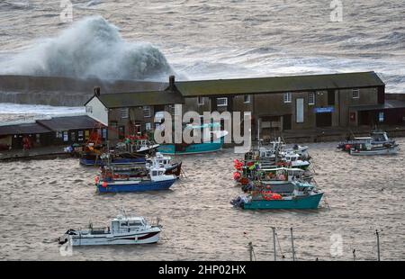 Vagues crash contre la Cobb dans Lyme Regis, Dorset ouest, comme la tempête Eunice frappe la côte sud, avec des attractions de fermeture, la perturbation de voyage et un incident majeur déclaré dans certaines régions, ce qui signifie que les gens sont avertis de rester à l'intérieur. Un avertissement rare de temps rouge - l'alerte la plus élevée, ce qui signifie qu'un impact élevé est très probable - a été émis par le bureau met en raison de la combinaison de marées hautes, de vents forts et de la montée de tempête. Date de la photo : vendredi 18 février 2022. Banque D'Images