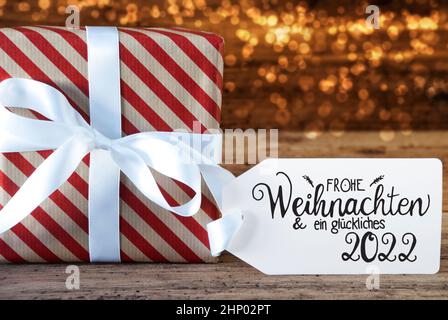 Un cadeau de Noël avec étiquette avec la calligraphie allemande Frohe Weihnachten und Ein Glueckliches 2022 signifie Joyeux Noël et Un heureux 2022. Pap. D'emballage Banque D'Images