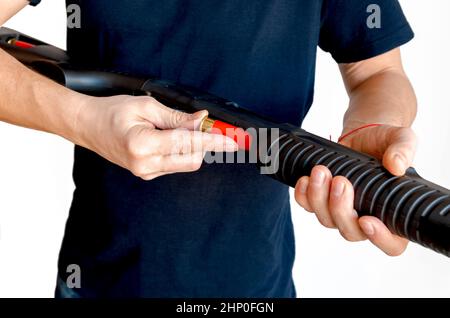 Gros plan de l'homme chargeant une carapace de fusil de chasse rouge dans le magazine de son arme. Charger une arme Smoothbore à pompe Banque D'Images