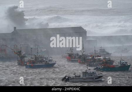 Vagues crash contre la Cobb dans Lyme Regis, Dorset ouest, comme la tempête Eunice frappe la côte sud, avec des attractions de fermeture, la perturbation de voyage et un incident majeur déclaré dans certaines régions, ce qui signifie que les gens sont avertis de rester à l'intérieur. Un avertissement rare de temps rouge - l'alerte la plus élevée, ce qui signifie qu'un impact élevé est très probable - a été émis par le bureau met en raison de la combinaison de marées hautes, de vents forts et de la montée de tempête. Date de la photo : vendredi 18 février 2022. Banque D'Images