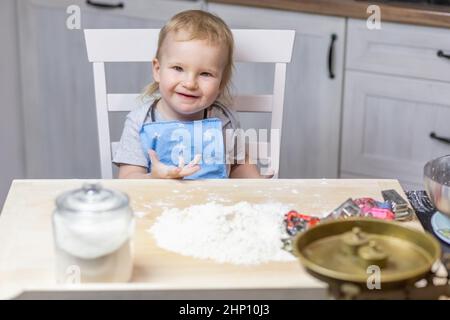 LLittle Cute garçon pose à la table prête à cuire des biscuits dans la cuisine. Banque D'Images