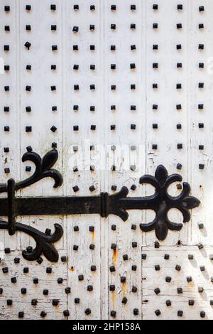 Porte blanche ornée de clous avec support en fer forgé Banque D'Images