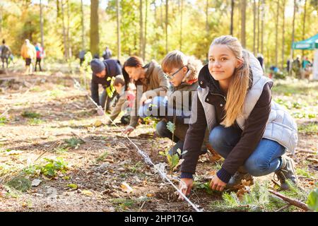 Groupe de volontaires et d'enfants plantant des arbres dans la forêt pour la durabilité et la protection du climat Banque D'Images