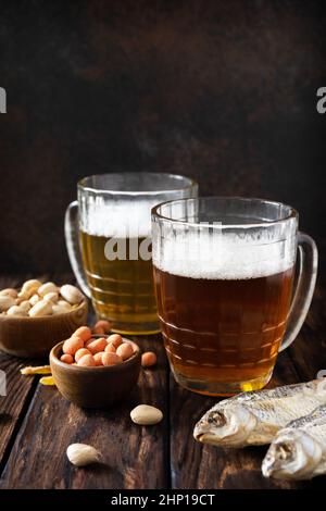 Alcool de bière lager et pinte de stout, bière artisanale. Deux verres de bière avec mousse et en-cas sur un fond rustique en bois. Traditionnel allemand Wha Banque D'Images